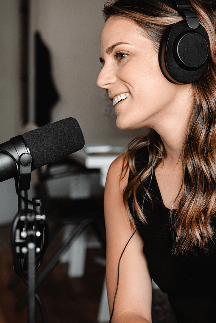 Brunette with headphones on in front of microphone