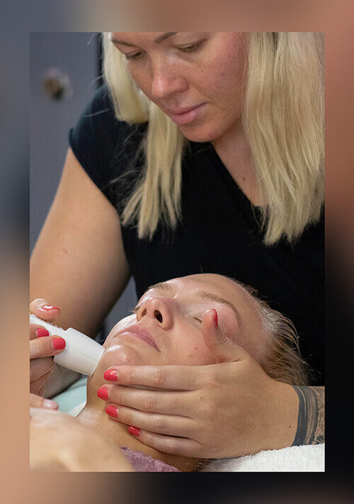 A technician performs shockwave facial treatment on a client